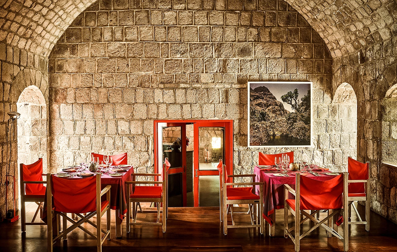 a table set up in a room with red chairs and red tablecloths