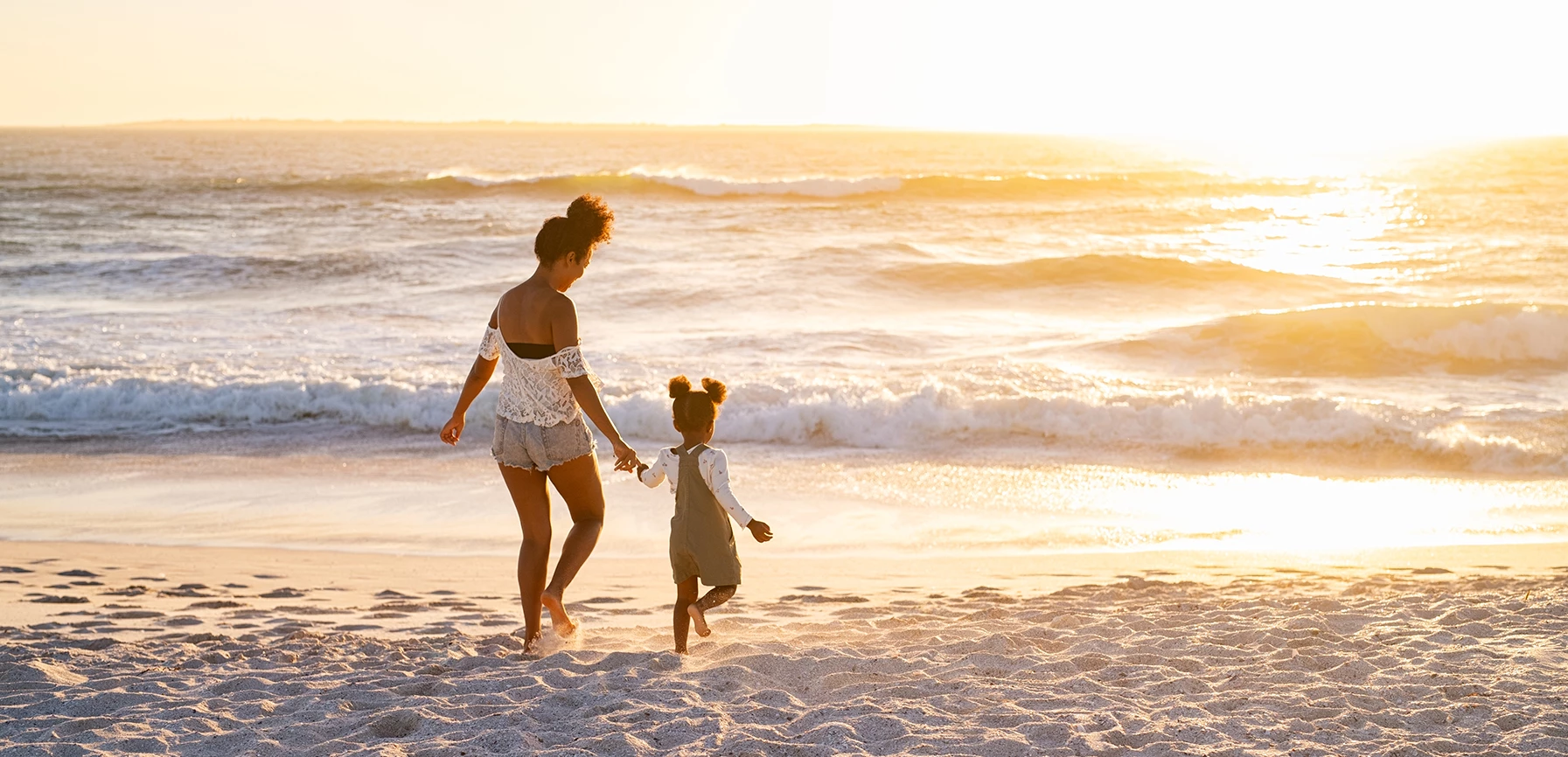 a woman and a child walking on a beach