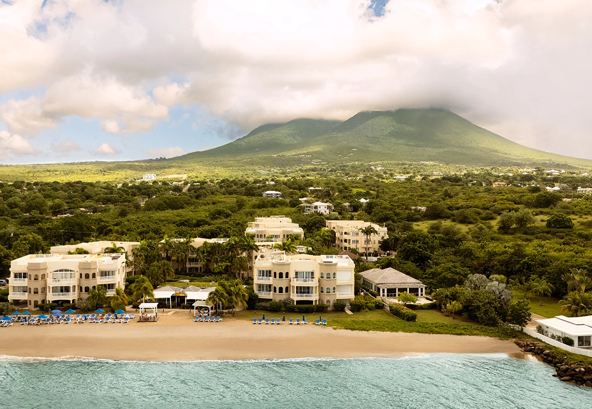 a beach with buildings and trees and a mountain in the background