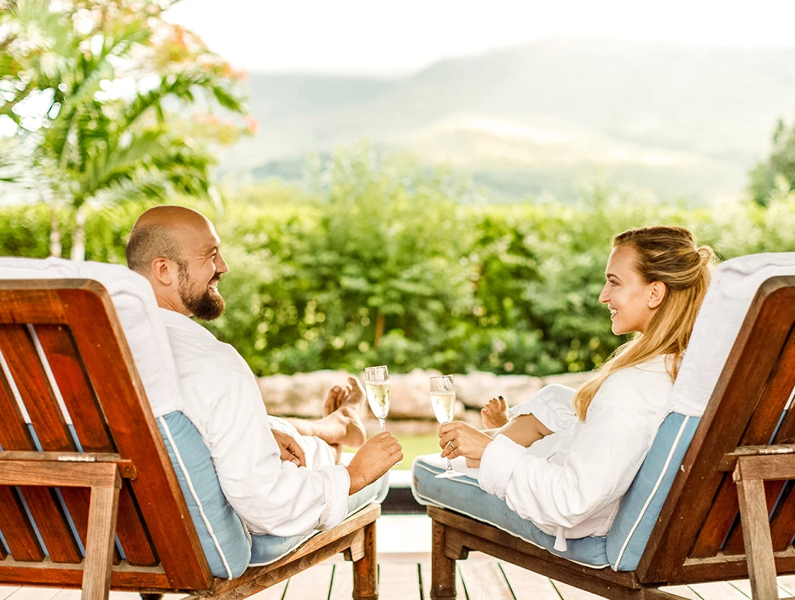 a man and woman in bathrobes sitting on chairs with drinks