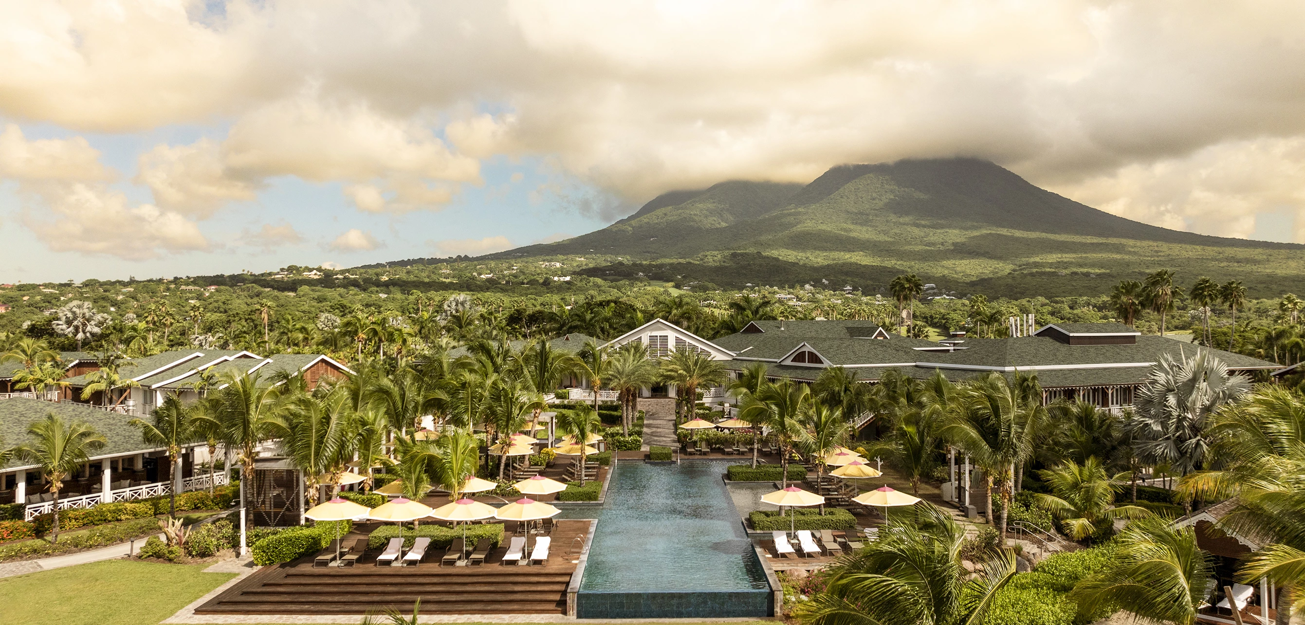 a pool with umbrellas and chairs in front of a resort