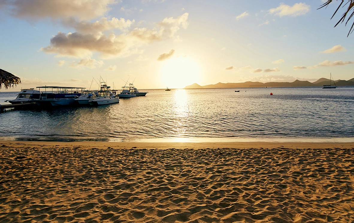 a beach with boats and a sunset