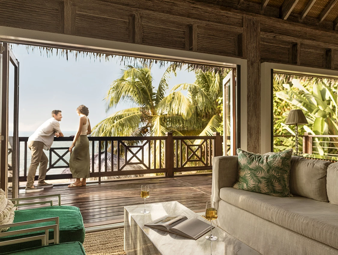 a couple of people standing on a deck overlooking a tropical beach