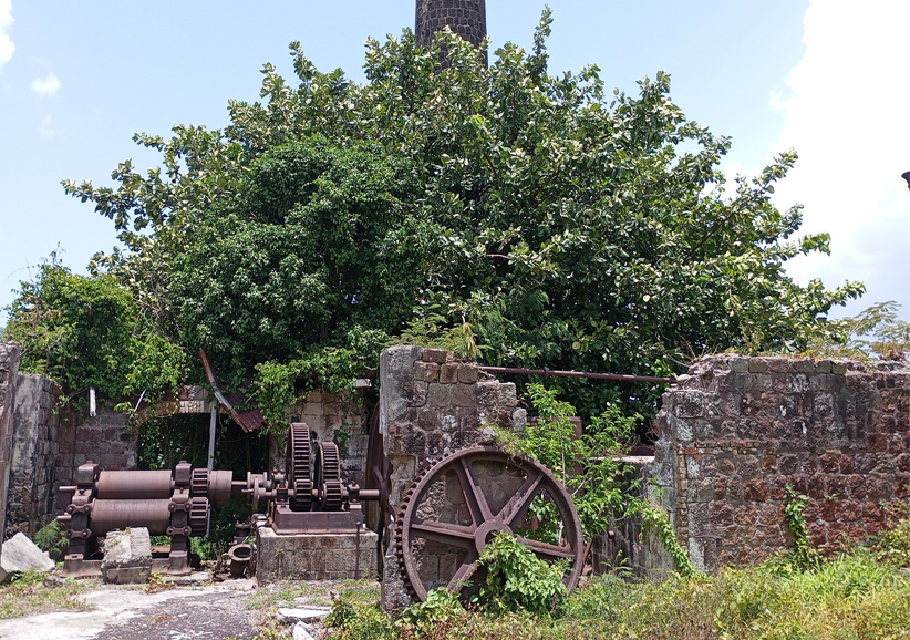 a large metal gears and a brick wall with a tower in the background