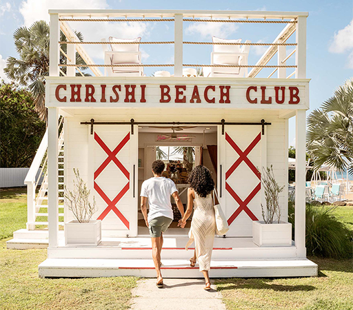 a man and woman walking towards a beach club