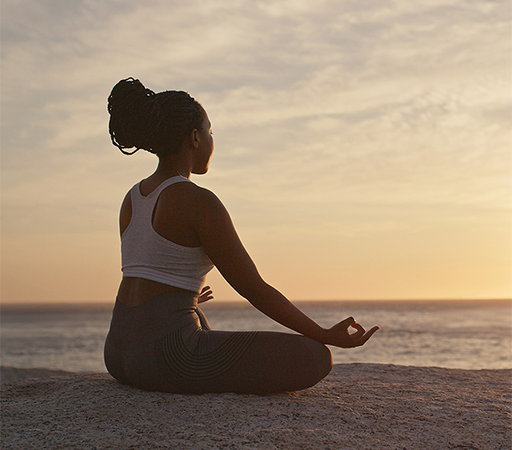 a woman sitting on a rock with her hands in the air
