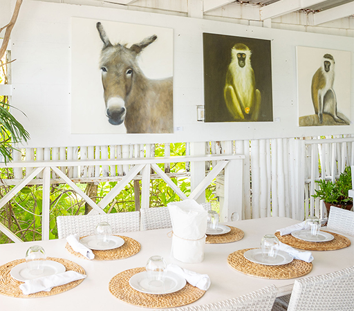 a table set for a dinner with a donkey and monkey paintings on the wall