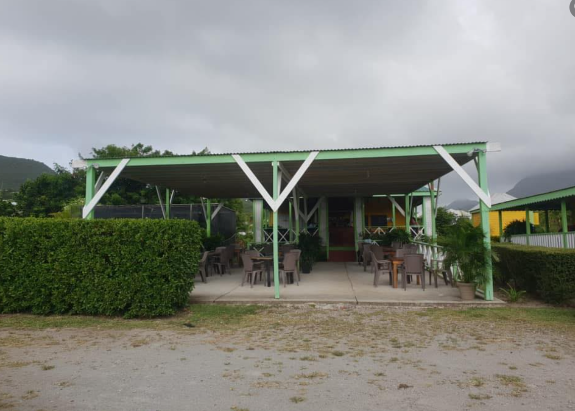 a green and white covered patio with tables and chairs