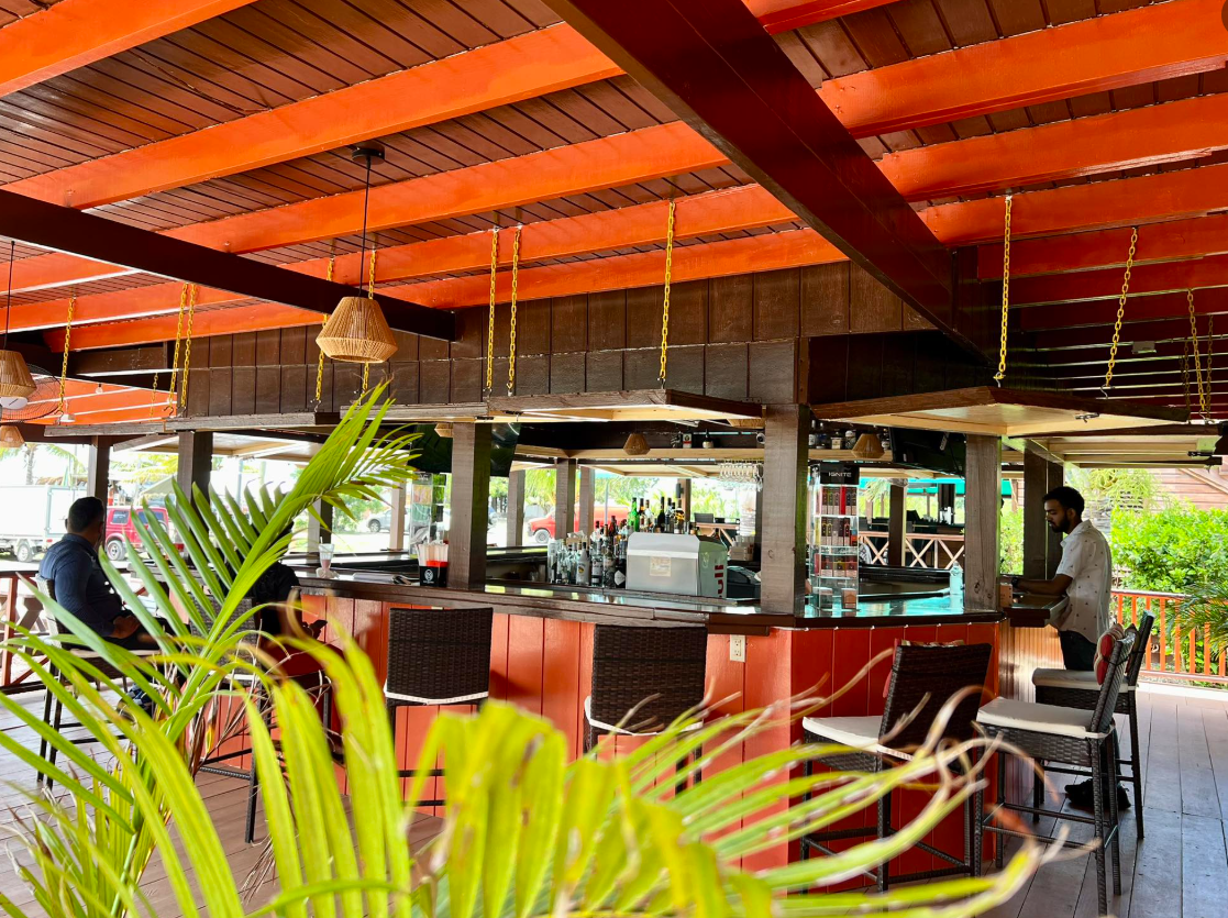 a bar with chairs and tables in a tropical setting