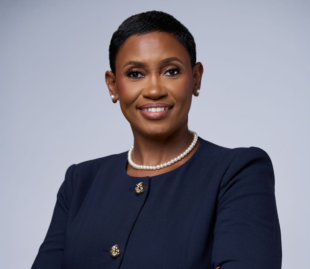 a woman wearing a pearl necklace and a blue jacket