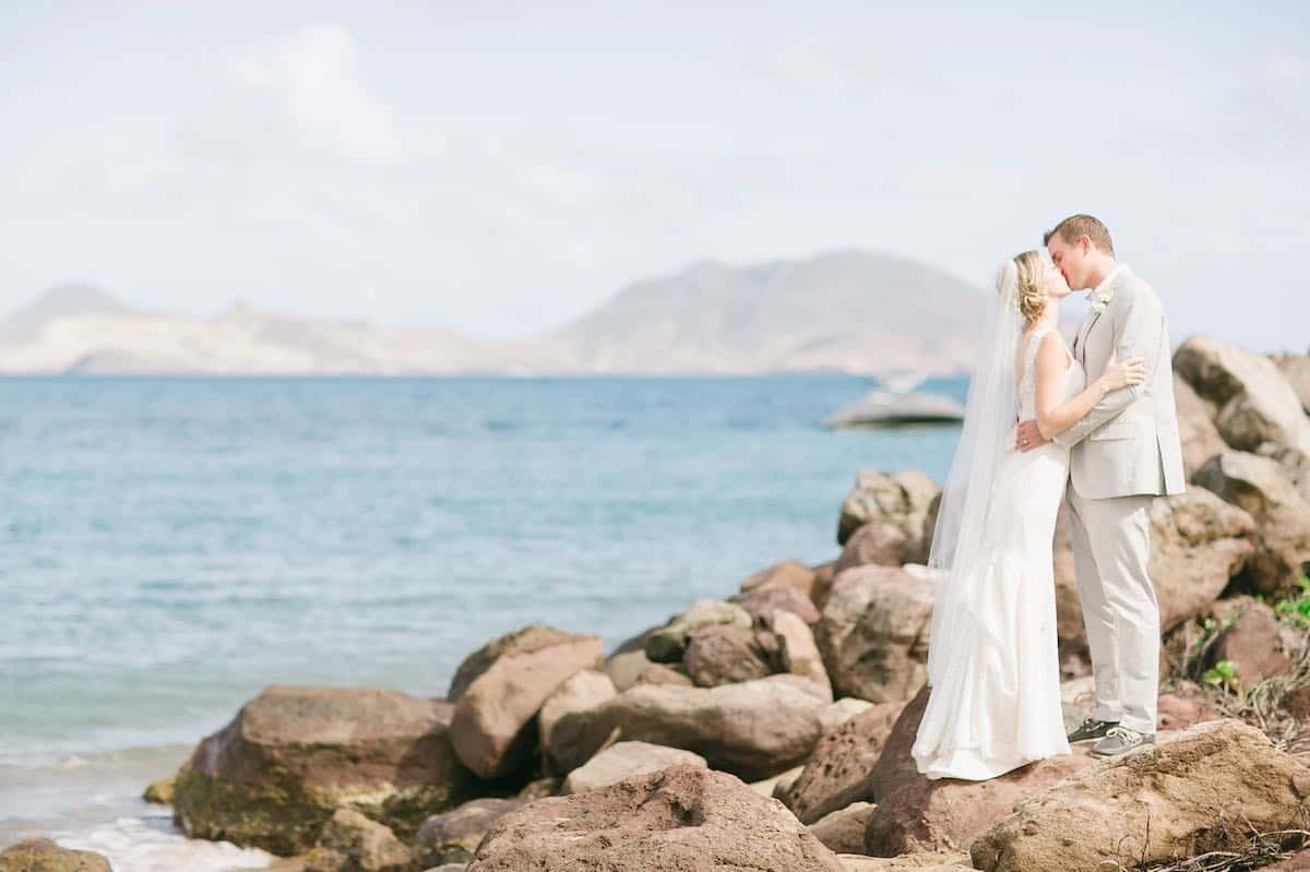 a man and woman kissing on a rocky beach