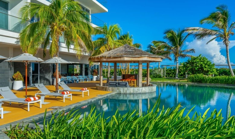 a pool with lounge chairs and umbrellas by a building