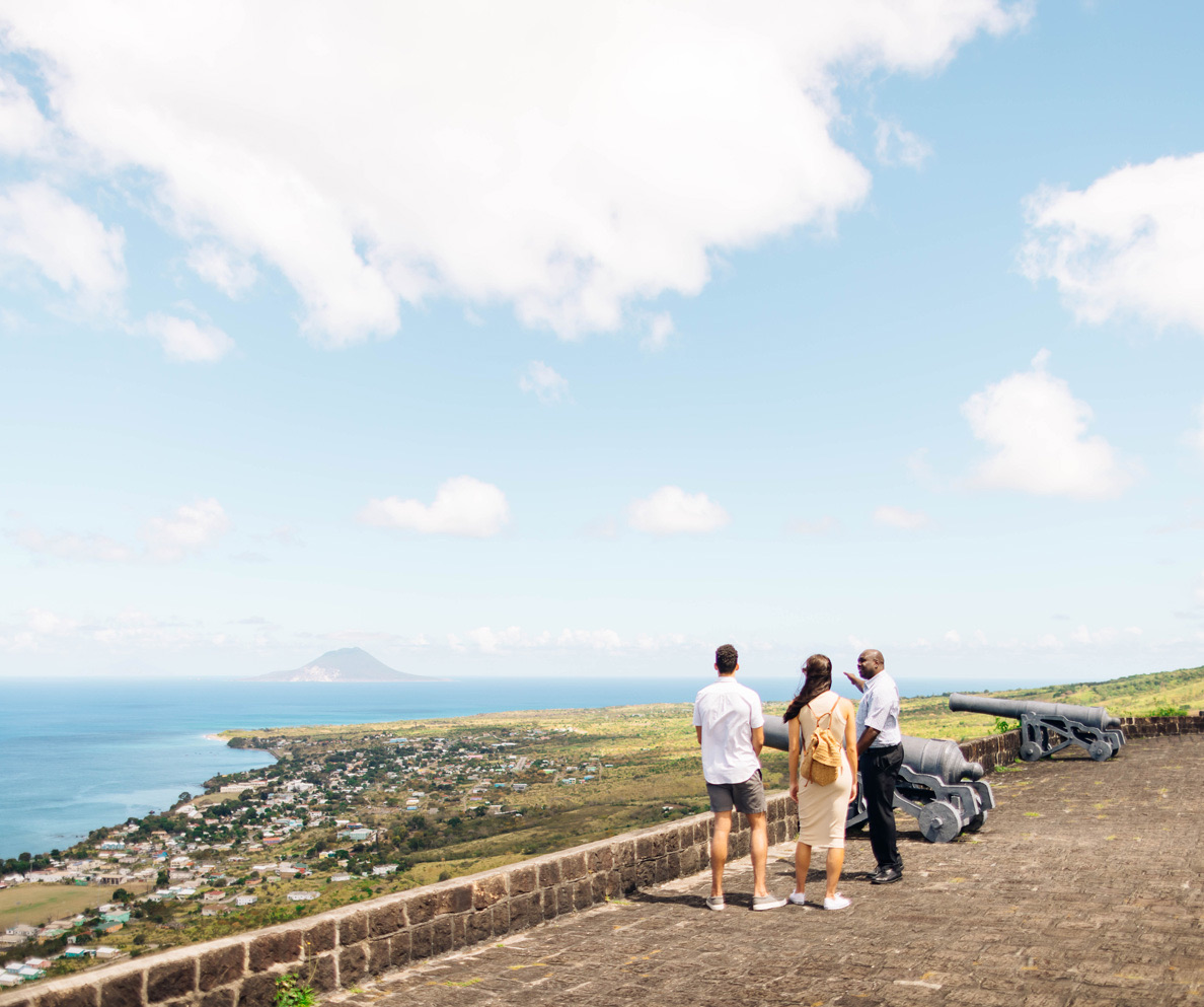 a group of people standing on a stone wall overlooking a body of water