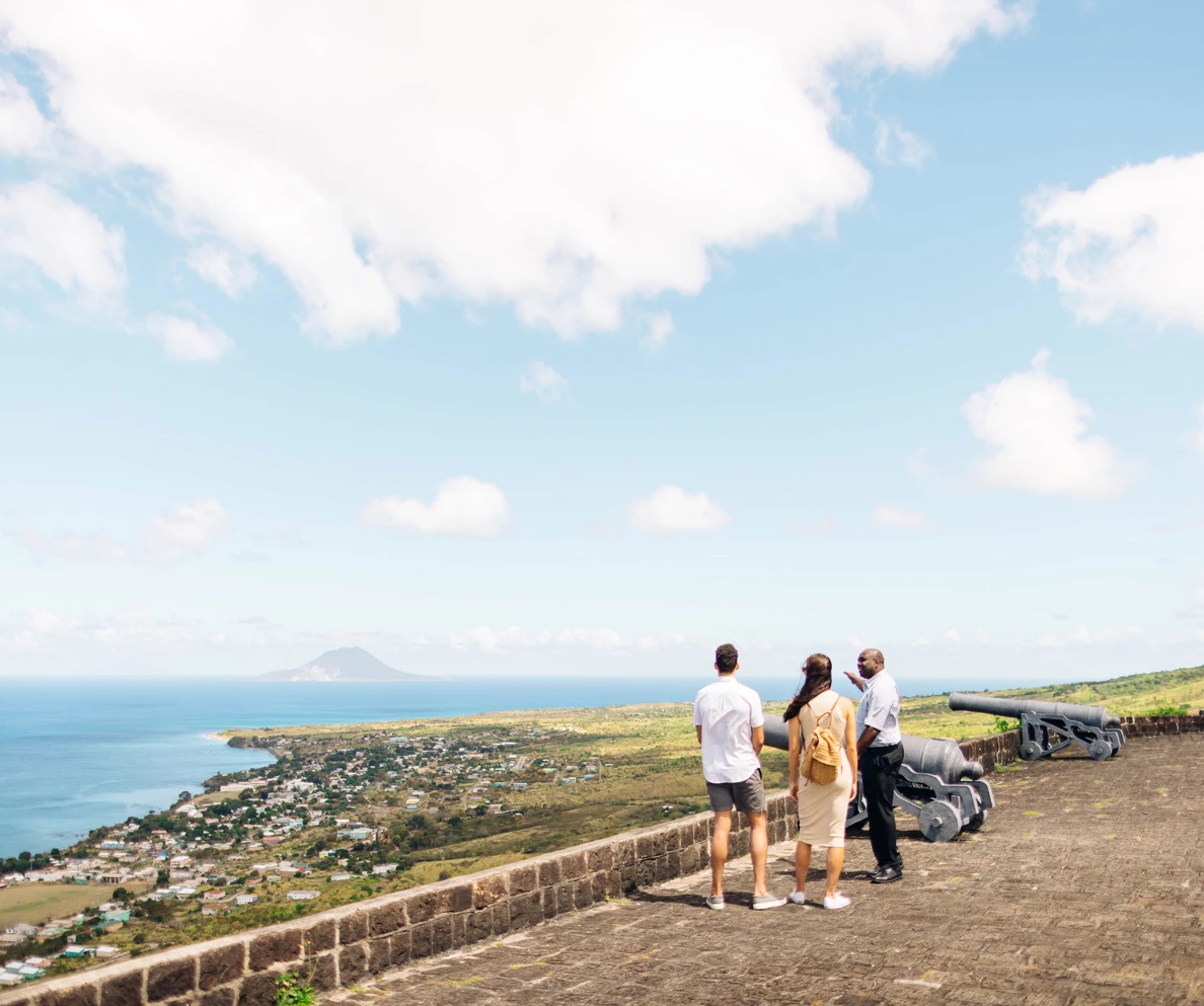 a group of people standing on a stone wall overlooking a body of water