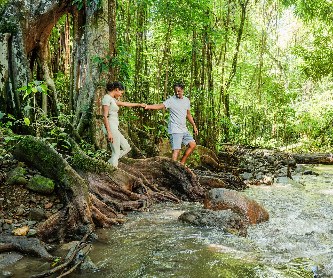 a man and woman standing on a rock in a forest