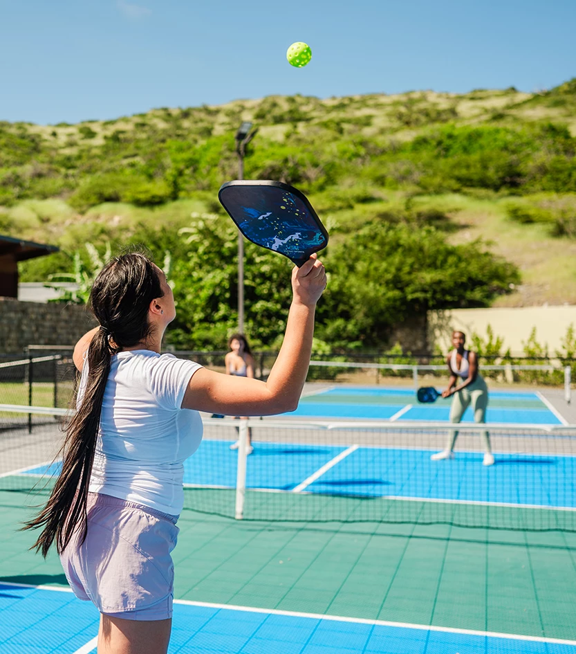 a woman hitting a tennis ball with a paddle