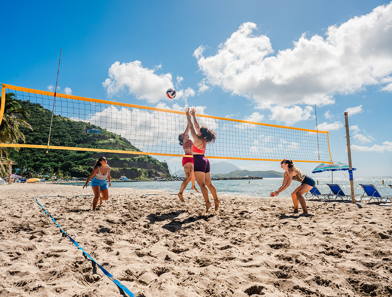 a group of people playing volleyball on a beach