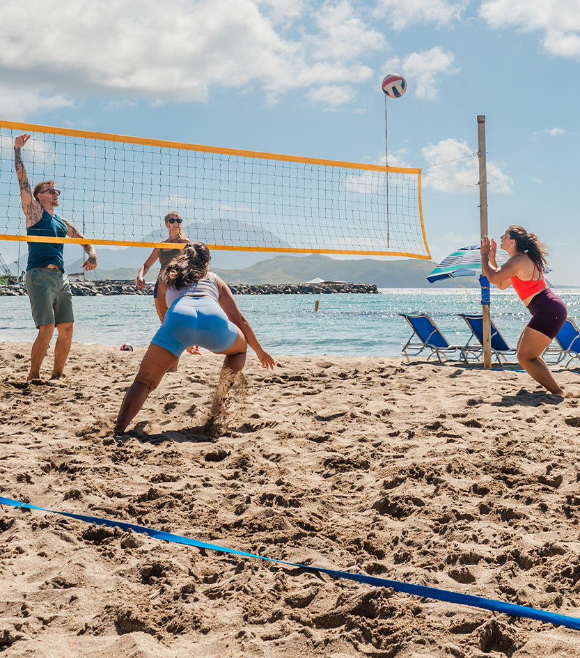 a group of people playing volleyball on a beach