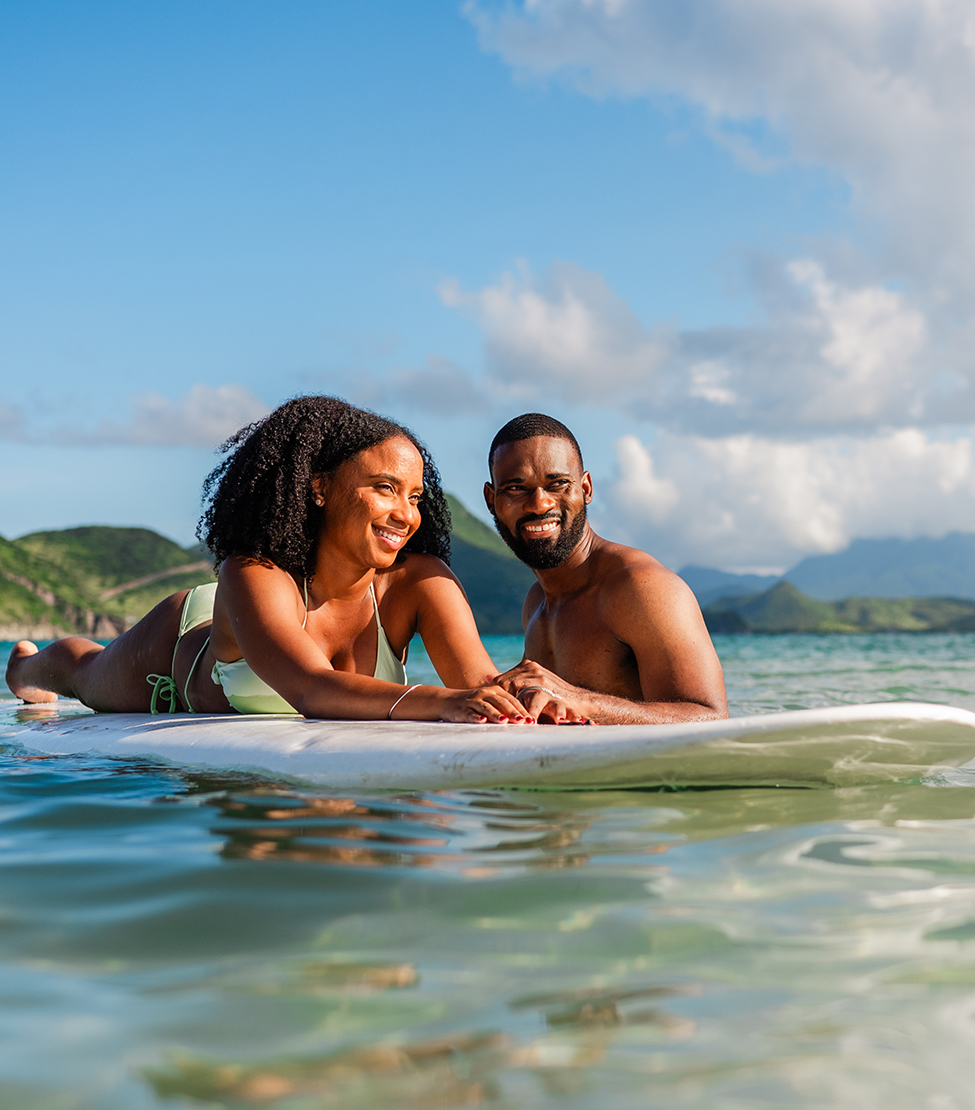 a man and woman lying on a surfboard in the water