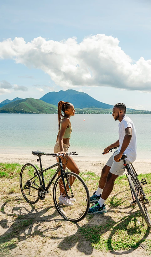 a man and woman on bicycles on a beach