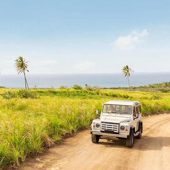 a car on a dirt road by a body of water