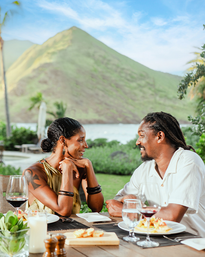 a man and woman sitting at a table with food and drinks