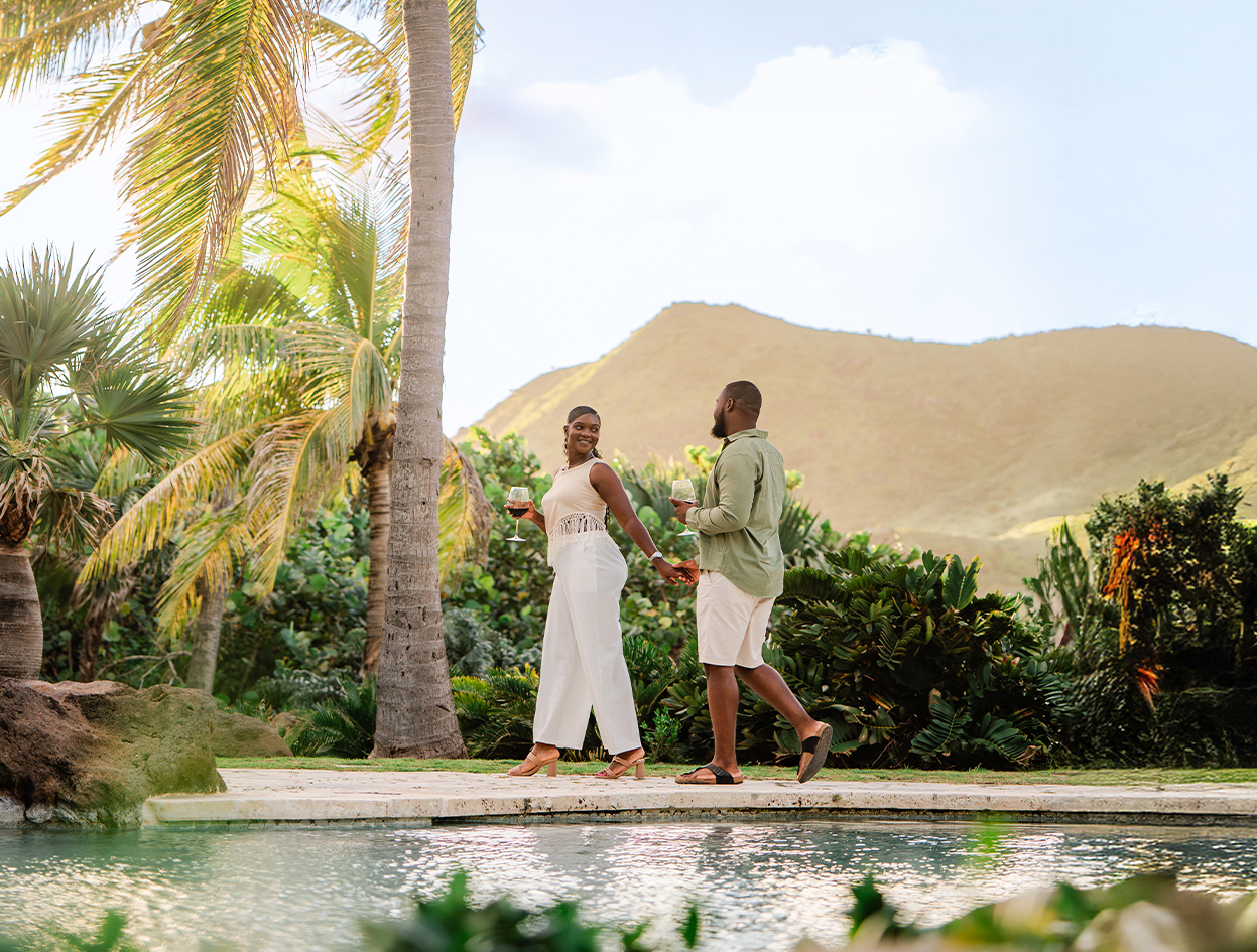 a man and woman holding hands by a pool