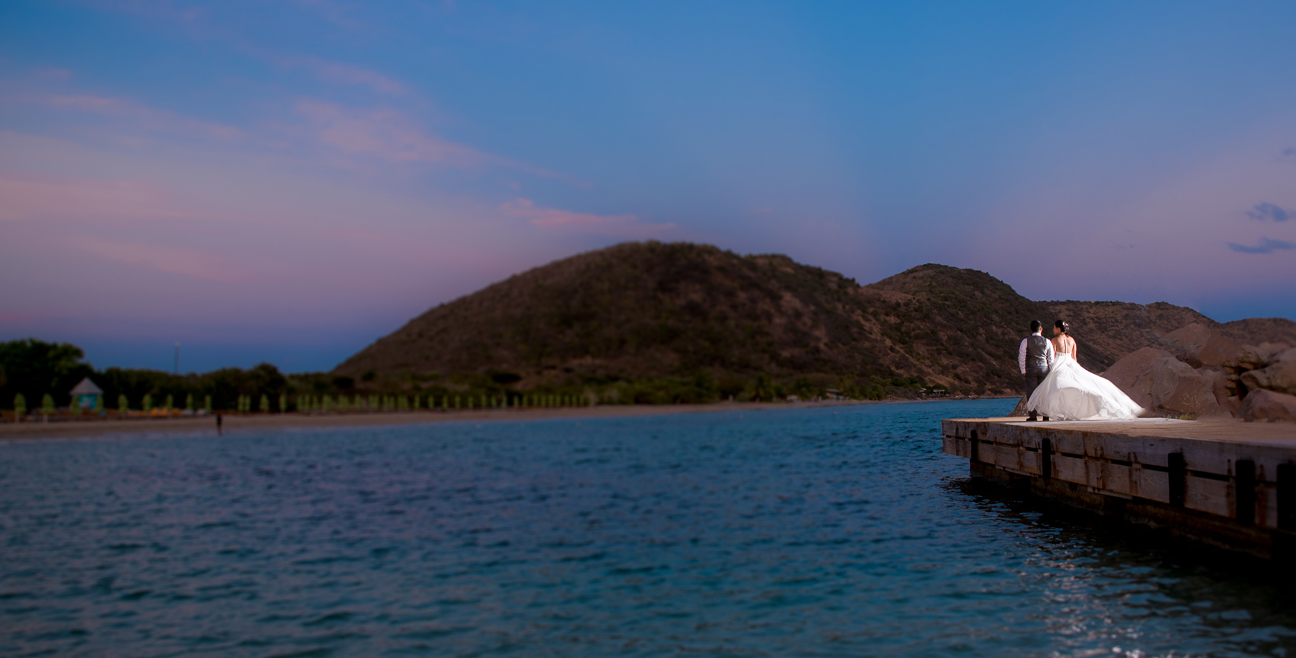a dock on a body of water with a hill in the background