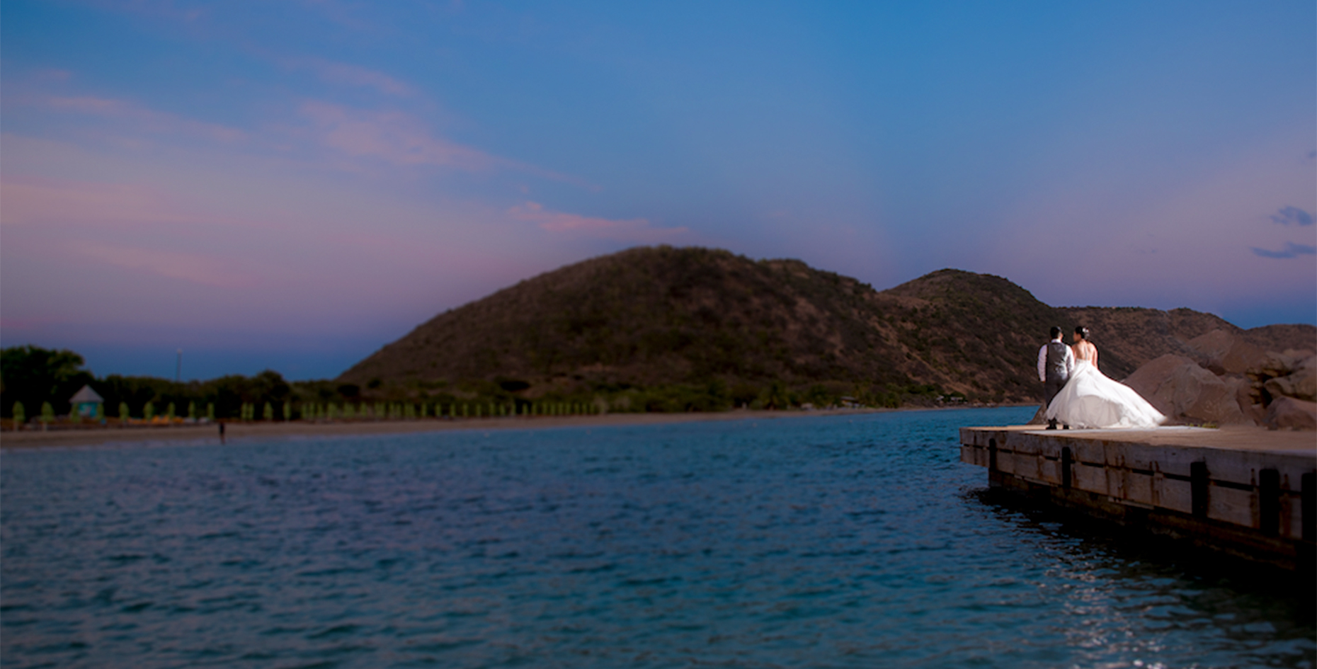 a dock on a body of water with a hill in the background