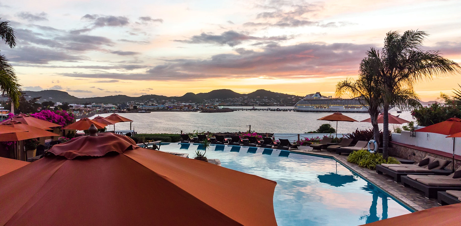a pool with umbrellas and chairs by a body of water