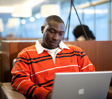 a man in an orange striped shirt working on a laptop