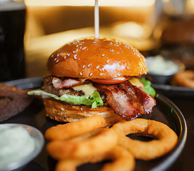 a burger with bacon and onion rings on a plate