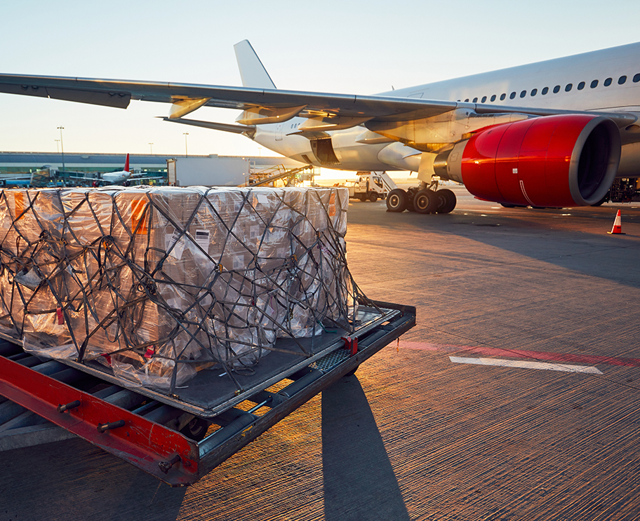 a luggage cart with a large white and red airplane in the background