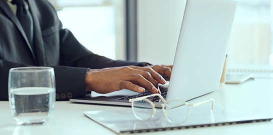 a close-up of a man's hands typing on a laptop
