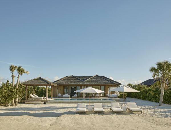 a beach house with lounge chairs and umbrellas