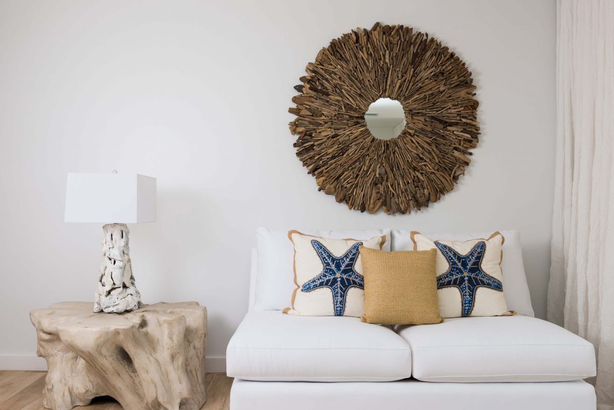 a white couch with pillows and a round mirror on the wall