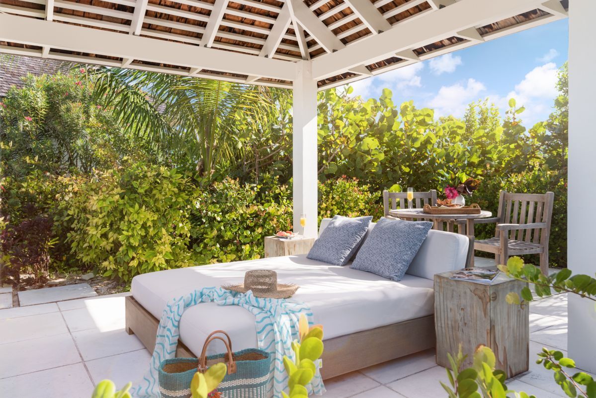 a outdoor patio with a white bed and a table and chairs