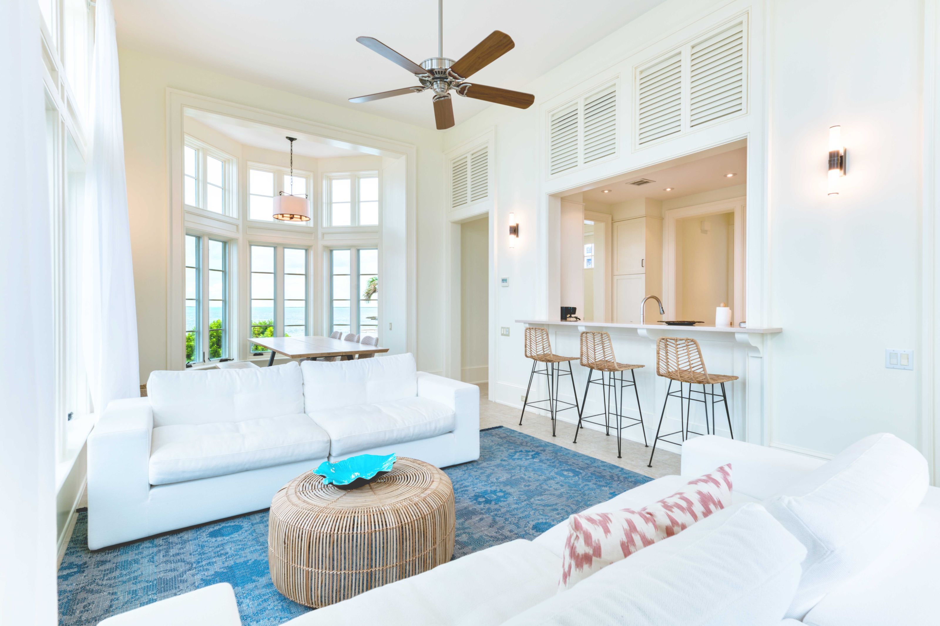 a living room with white furniture and a blue rug