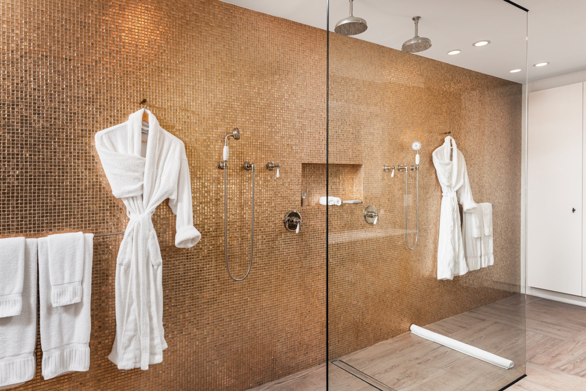 a shower with white bathrobes and shower heads