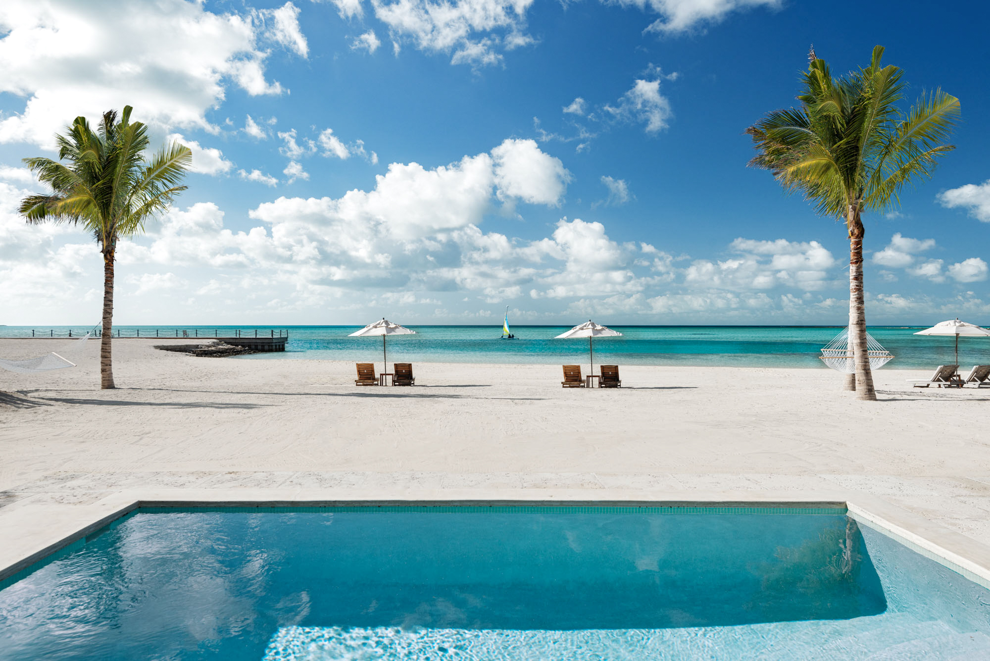a pool and chairs on a beach