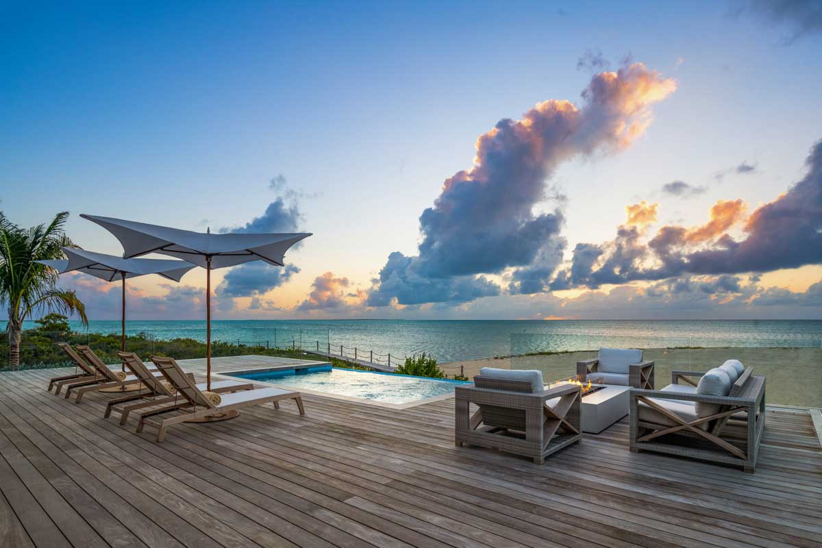 a deck with chairs and a pool on the beach