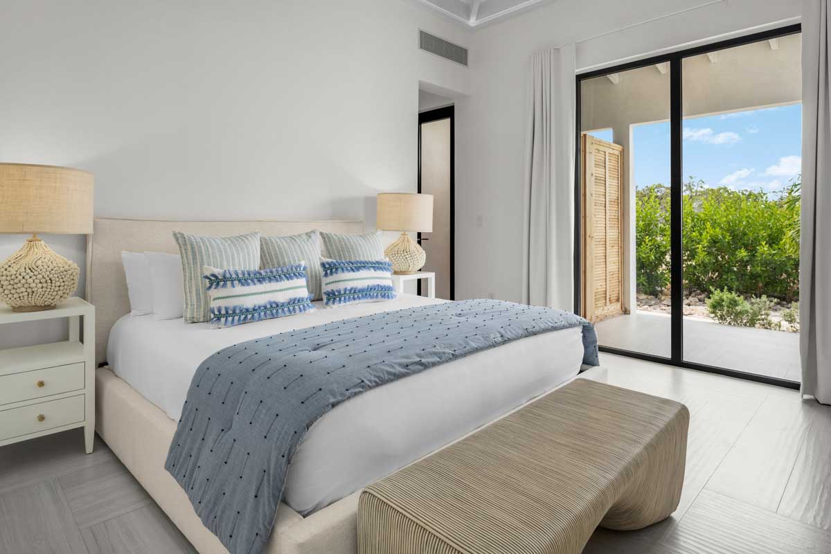 a bed with a bench and a lamp in a room with glass doors