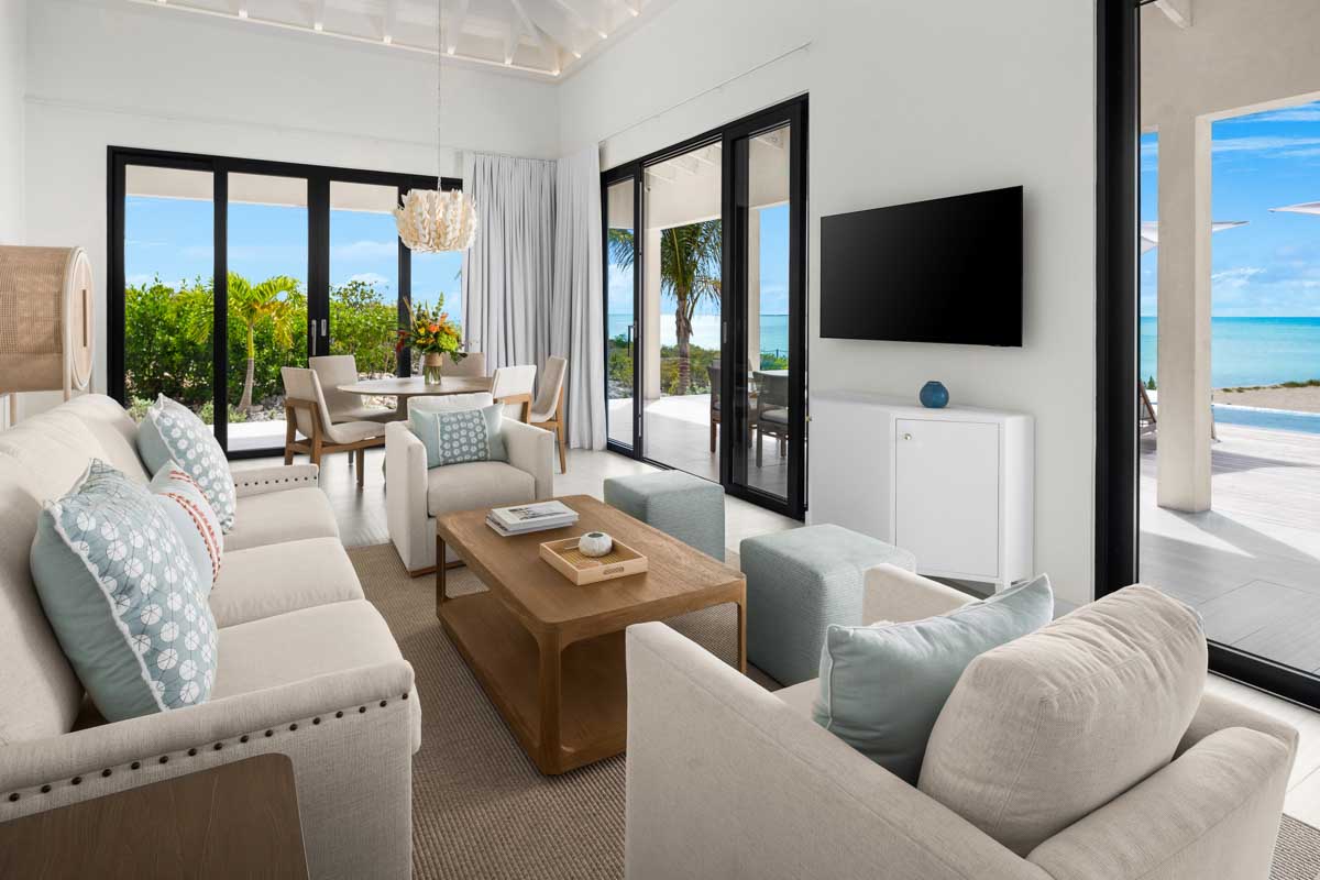 a living room with white furniture and a television