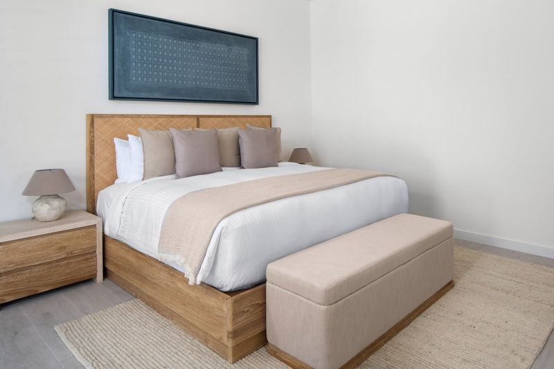 a bed with a bench and a painting above it