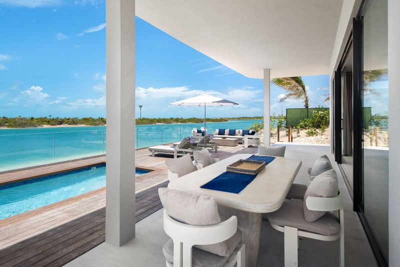 a table and chairs on a deck with a pool in the background
