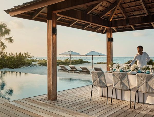 a table set up on a deck with chairs and umbrellas