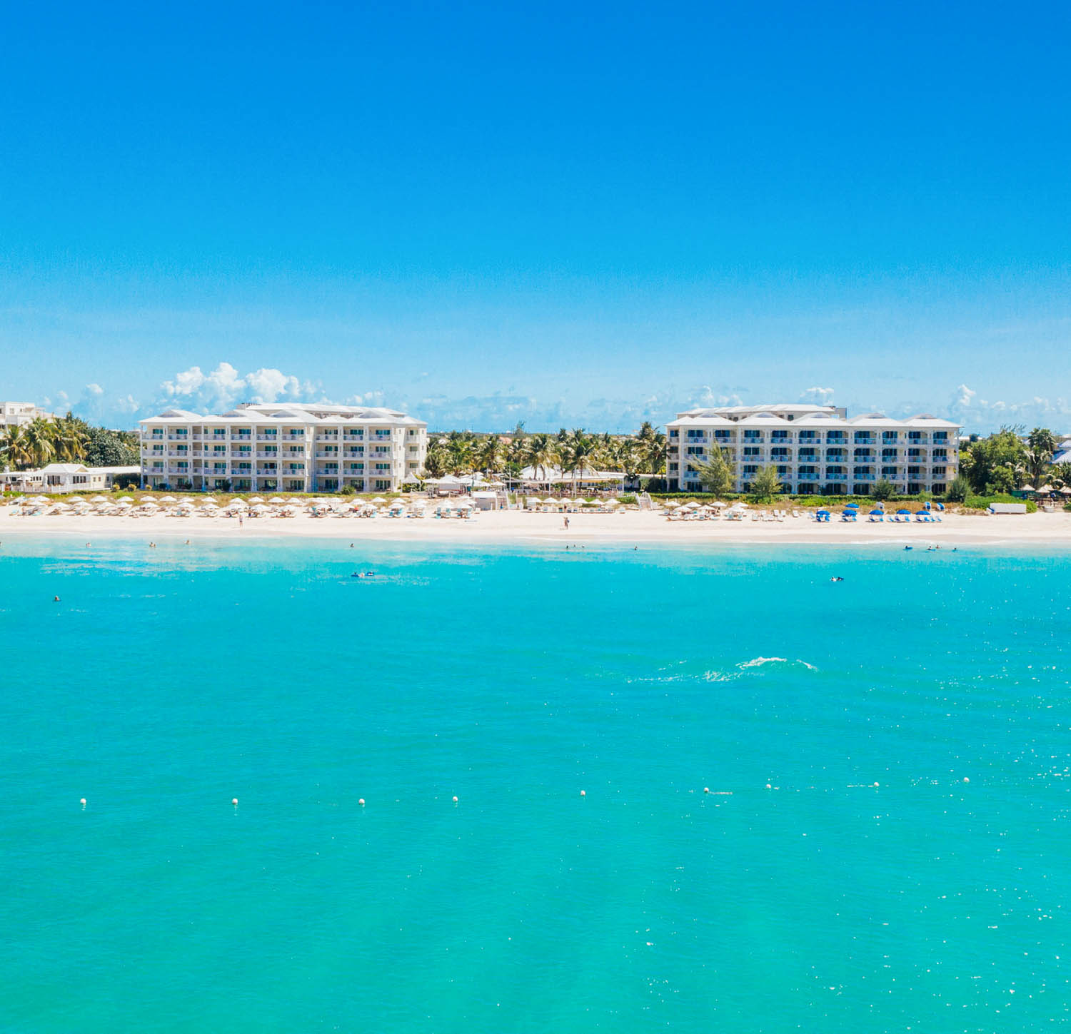 a beach with buildings and blue water