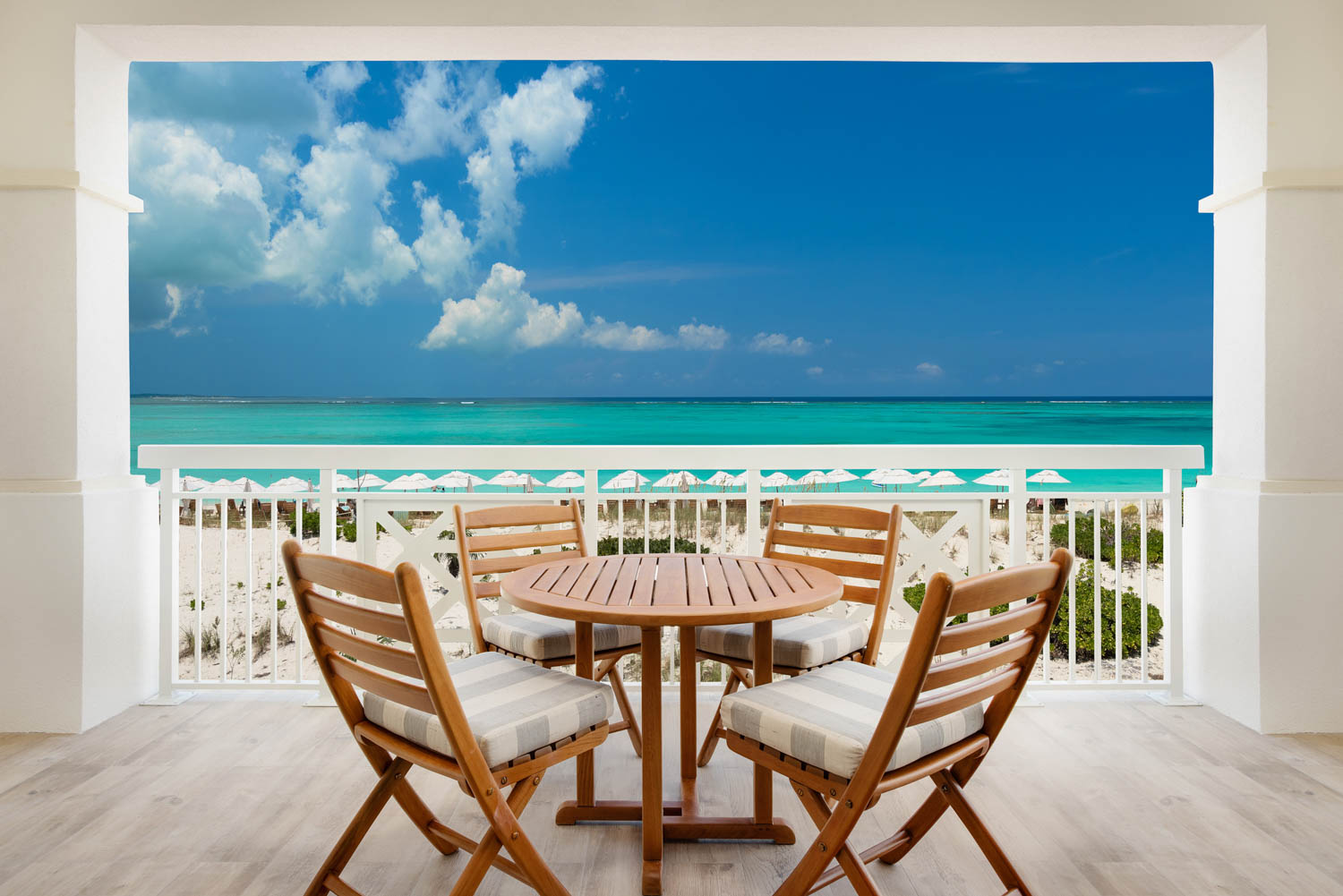 a table and chairs on a balcony overlooking the ocean