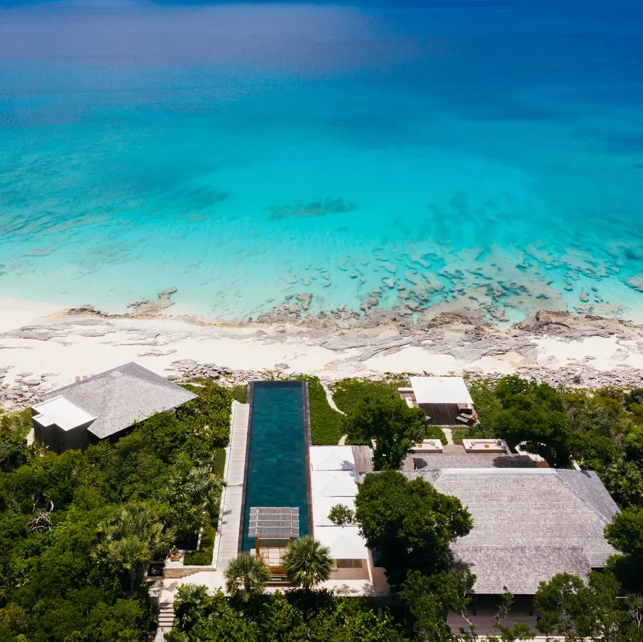 a house with a pool and trees on a beach