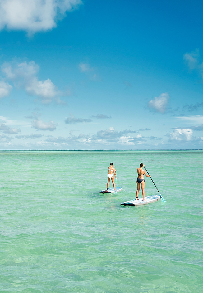 a couple of women on paddle boards in the ocean